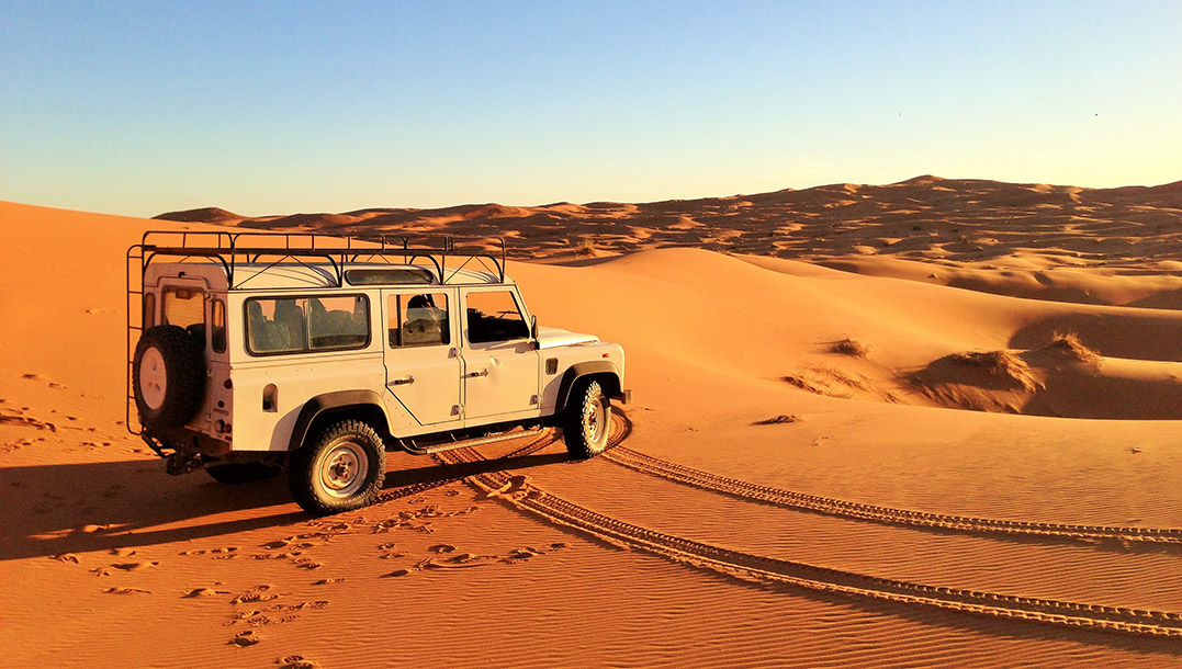 Beige Land Rover Defender in the middle of a desert