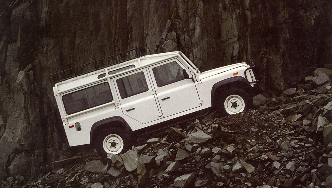 White Land Rover Defender 110 navigating rocky terrain